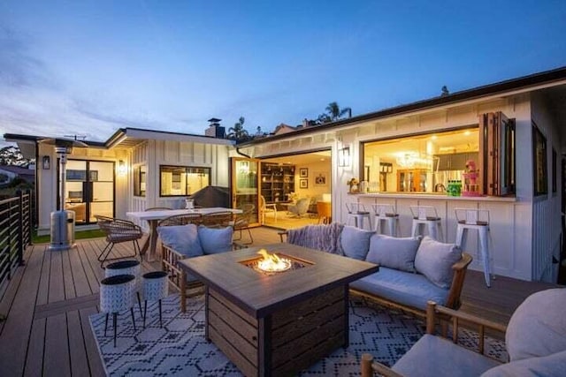 wooden deck with outdoor dry bar and an outdoor living space with a fire pit