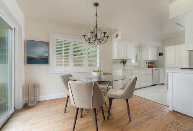 dining space featuring light wood finished floors, baseboards, visible vents, and a chandelier