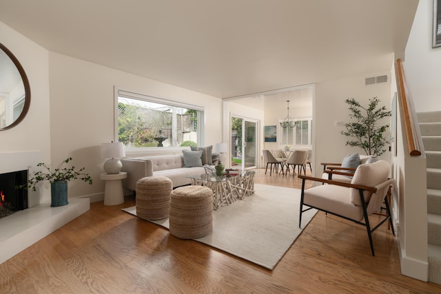 sitting room featuring a lit fireplace, stairs, visible vents, and wood finished floors