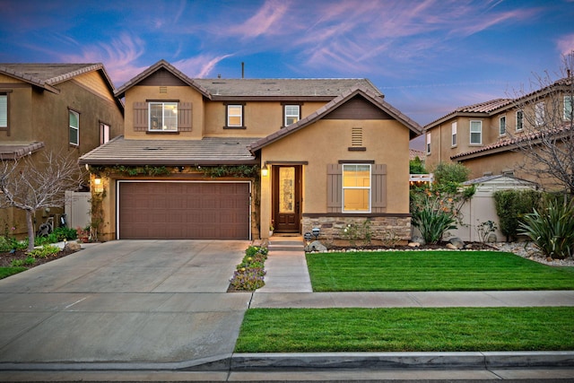 view of front of home featuring a yard, stucco siding, stone siding, driveway, and a tiled roof