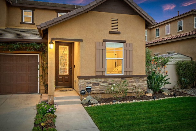 property entrance featuring a garage, stone siding, and stucco siding