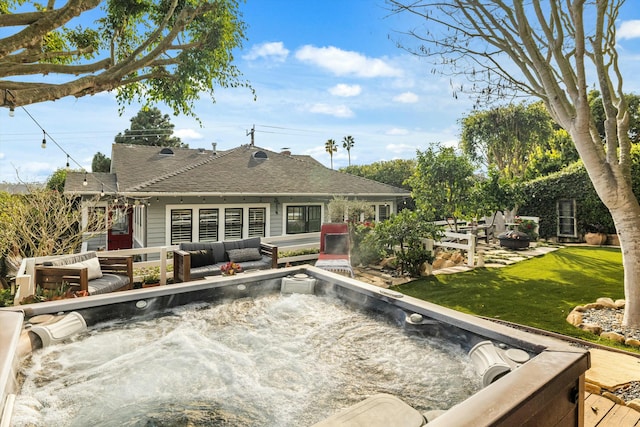 rear view of house with a hot tub, outdoor lounge area, a shingled roof, and a yard