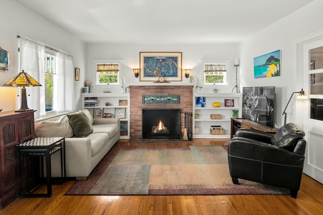 living room featuring a brick fireplace and wood finished floors