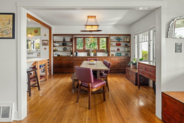 dining area with light wood finished floors and visible vents