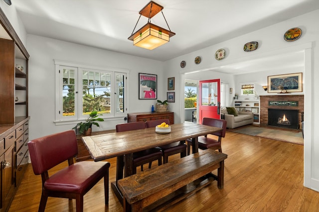 dining area with light wood finished floors and a fireplace