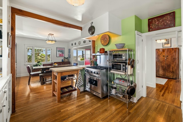 kitchen with light countertops, appliances with stainless steel finishes, white cabinetry, beamed ceiling, and hardwood / wood-style flooring