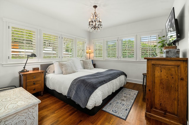 bedroom with an inviting chandelier, multiple windows, and dark wood finished floors