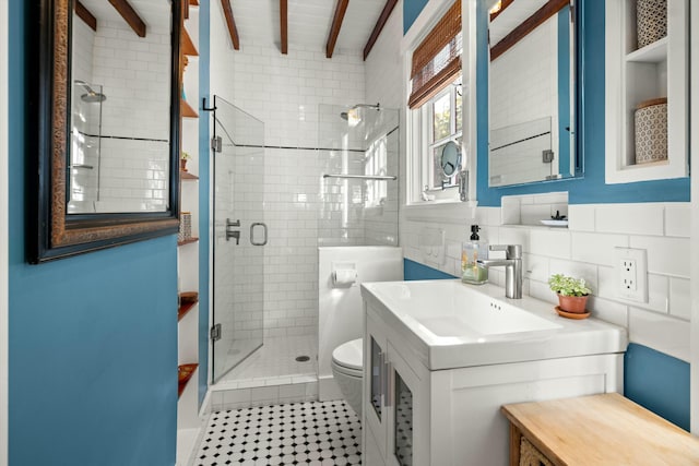 bathroom with tile walls, toilet, a shower stall, vanity, and beamed ceiling