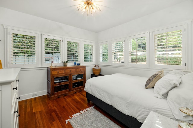 bedroom with an inviting chandelier, dark wood finished floors, and baseboards