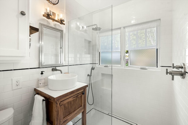 full bathroom featuring toilet, tile walls, vanity, and a walk in shower