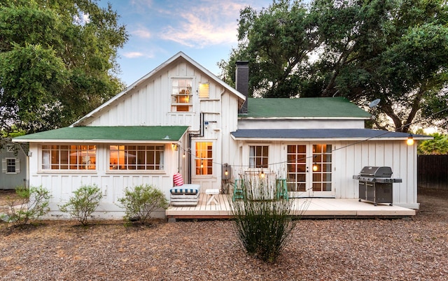 back of house with french doors, board and batten siding, a chimney, and a wooden deck