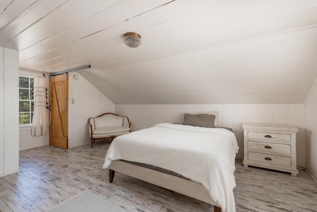 bedroom with lofted ceiling and light wood finished floors