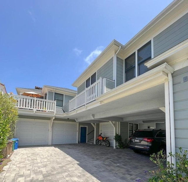 exterior space with an attached garage, decorative driveway, and a balcony