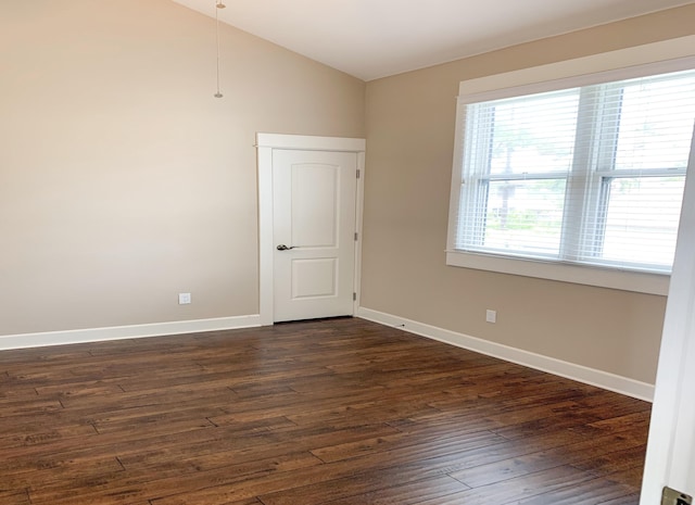 empty room with baseboards, dark wood-style floors, and vaulted ceiling