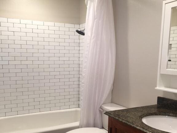 bathroom featuring shower / bath combo with shower curtain, toilet, and vanity