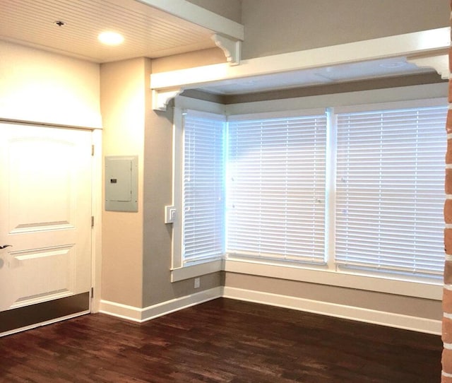 unfurnished room with recessed lighting, electric panel, wood finished floors, and baseboards