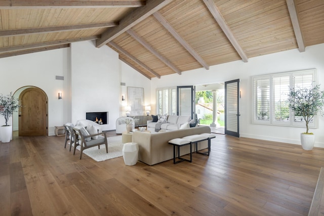 living area with a large fireplace, beam ceiling, high vaulted ceiling, baseboards, and wood finished floors