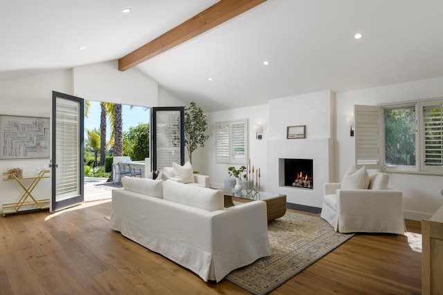 living room with a warm lit fireplace, baseboards, recessed lighting, wood finished floors, and vaulted ceiling with beams