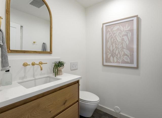 bathroom with toilet, vanity, and baseboards