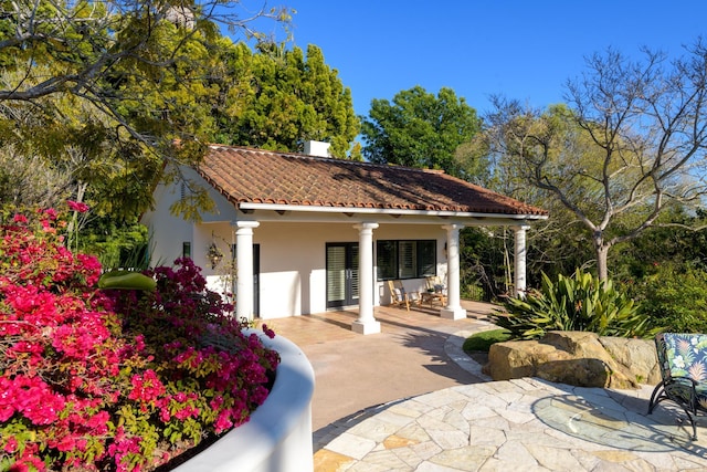exterior space with stucco siding and a tile roof