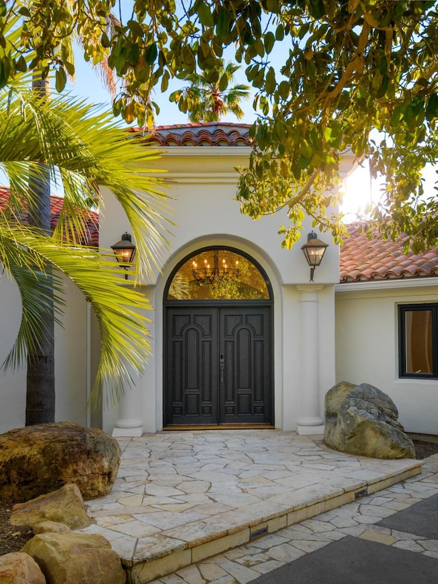 view of exterior entry with stucco siding and a tiled roof