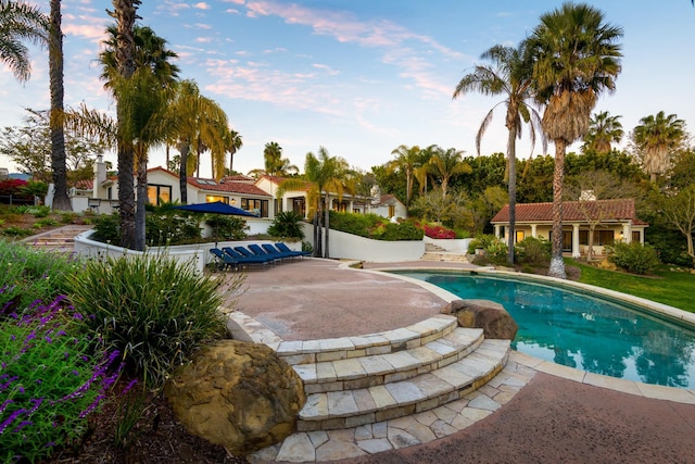 pool with an outdoor structure, a patio, and a storage structure