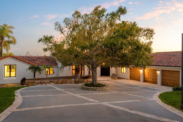 mediterranean / spanish-style house with driveway, stucco siding, an attached garage, and a tile roof