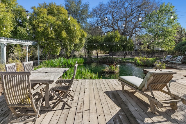 dock area with outdoor dining area, a deck with water view, and fence