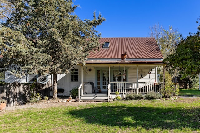 back of property featuring metal roof, a lawn, a porch, and fence