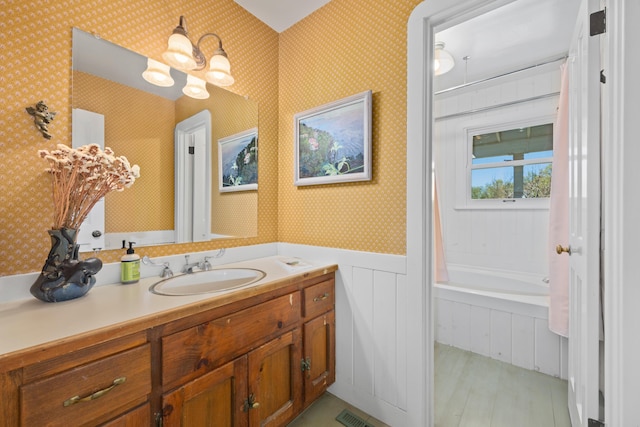 full bath with vanity, visible vents, wallpapered walls, wainscoting, and a bath