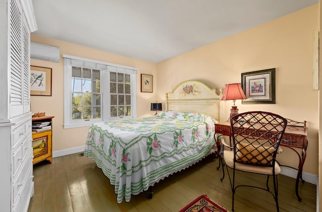 bedroom with hardwood / wood-style floors, an AC wall unit, and baseboards