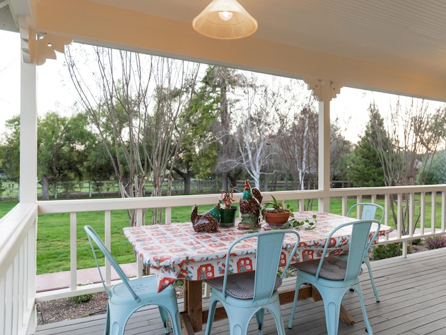 wooden deck featuring outdoor dining area, a lawn, and ceiling fan