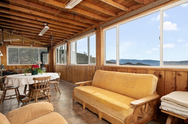 sunroom featuring a wood stove, wooden ceiling, a mountain view, and beamed ceiling