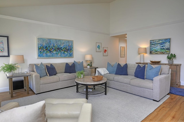 living area featuring high vaulted ceiling, crown molding, baseboards, and wood finished floors