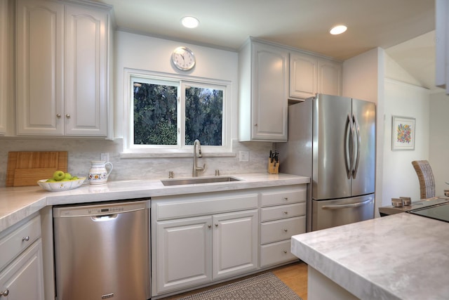 kitchen featuring a sink, backsplash, appliances with stainless steel finishes, and light countertops