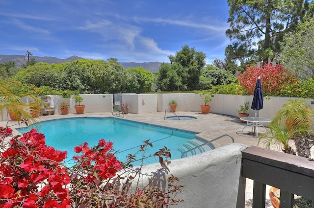 view of pool with fence, a patio area, and a mountain view