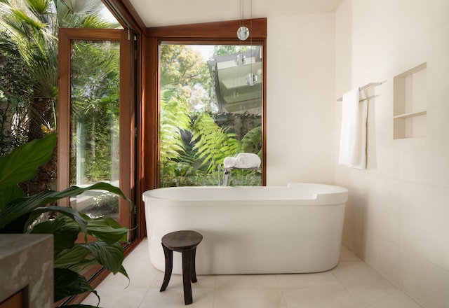 full bathroom with tile patterned flooring, a soaking tub, and tile walls