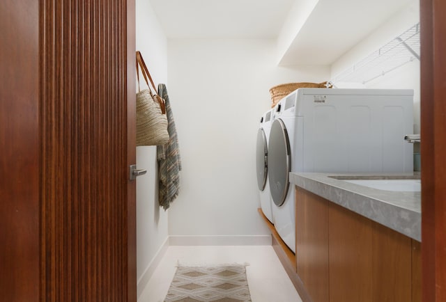 washroom featuring light tile patterned floors, baseboards, laundry area, and washer and clothes dryer