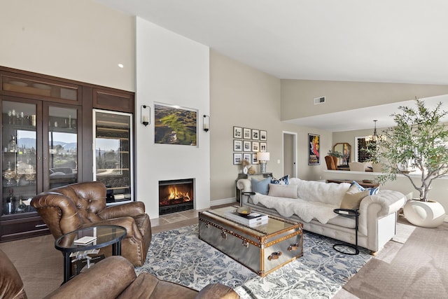 living area with high vaulted ceiling, a fireplace with flush hearth, and visible vents