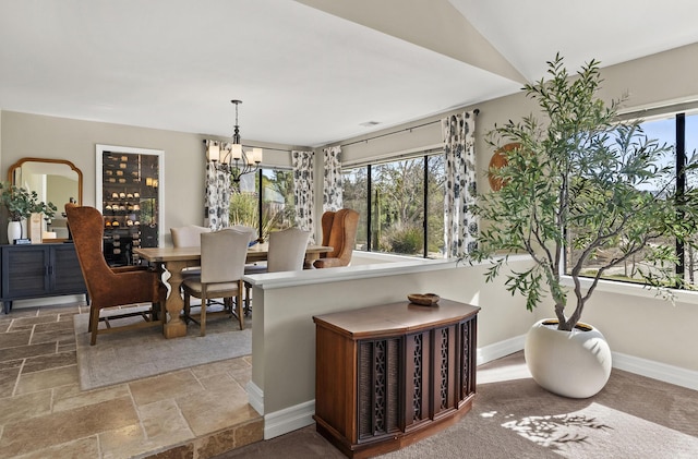 dining room with baseboards, an inviting chandelier, and stone tile floors