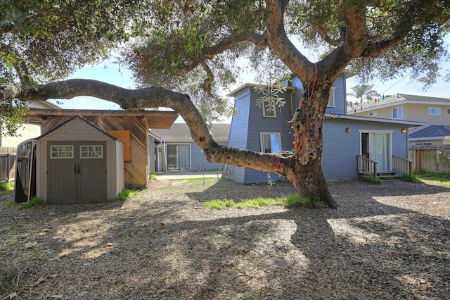 back of property with an outbuilding, entry steps, fence, and a shed