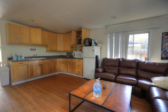 kitchen with white appliances, a sink, open floor plan, and wood finished floors