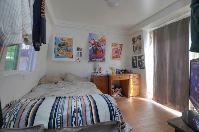 bedroom with crown molding and wood finished floors