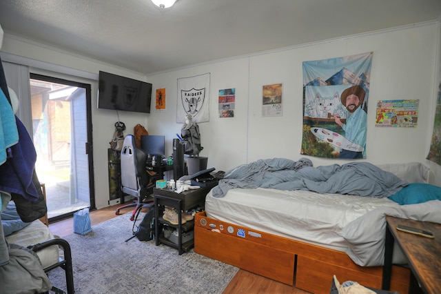 bedroom with wood finished floors and crown molding