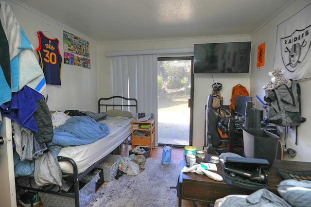 bedroom featuring ornamental molding, wood finished floors, and access to exterior