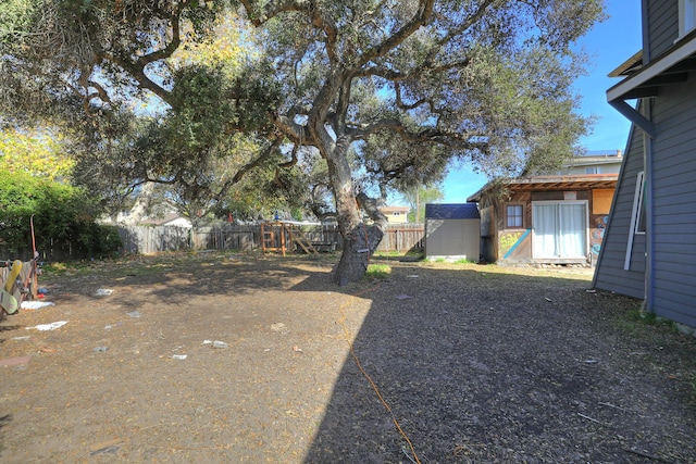 view of yard featuring an outbuilding, a storage unit, and fence