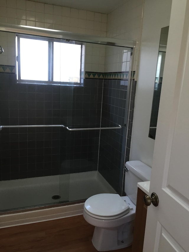 bathroom featuring tiled shower, wood finished floors, and toilet