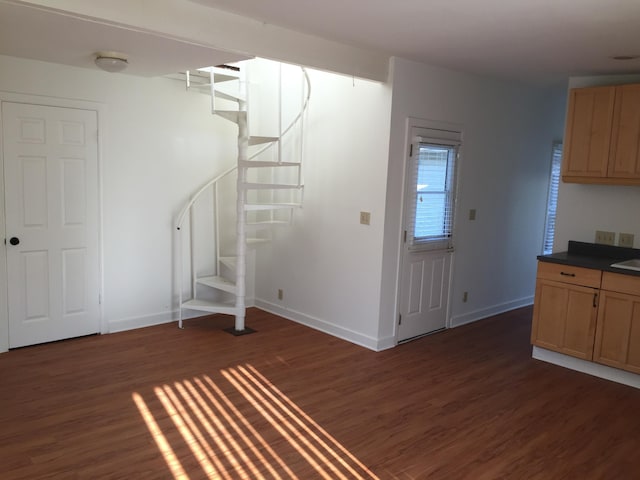 interior space with stairs, dark wood-style flooring, and baseboards