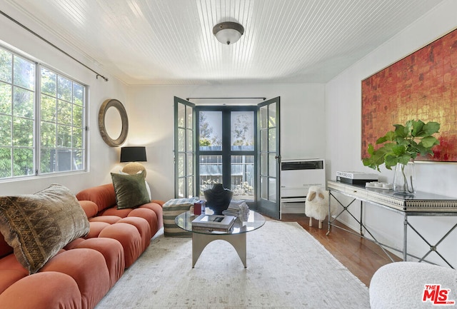 living area featuring heating unit, wood finished floors, and french doors