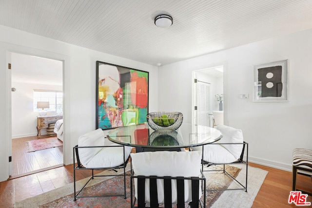 dining area with wood-type flooring and baseboards